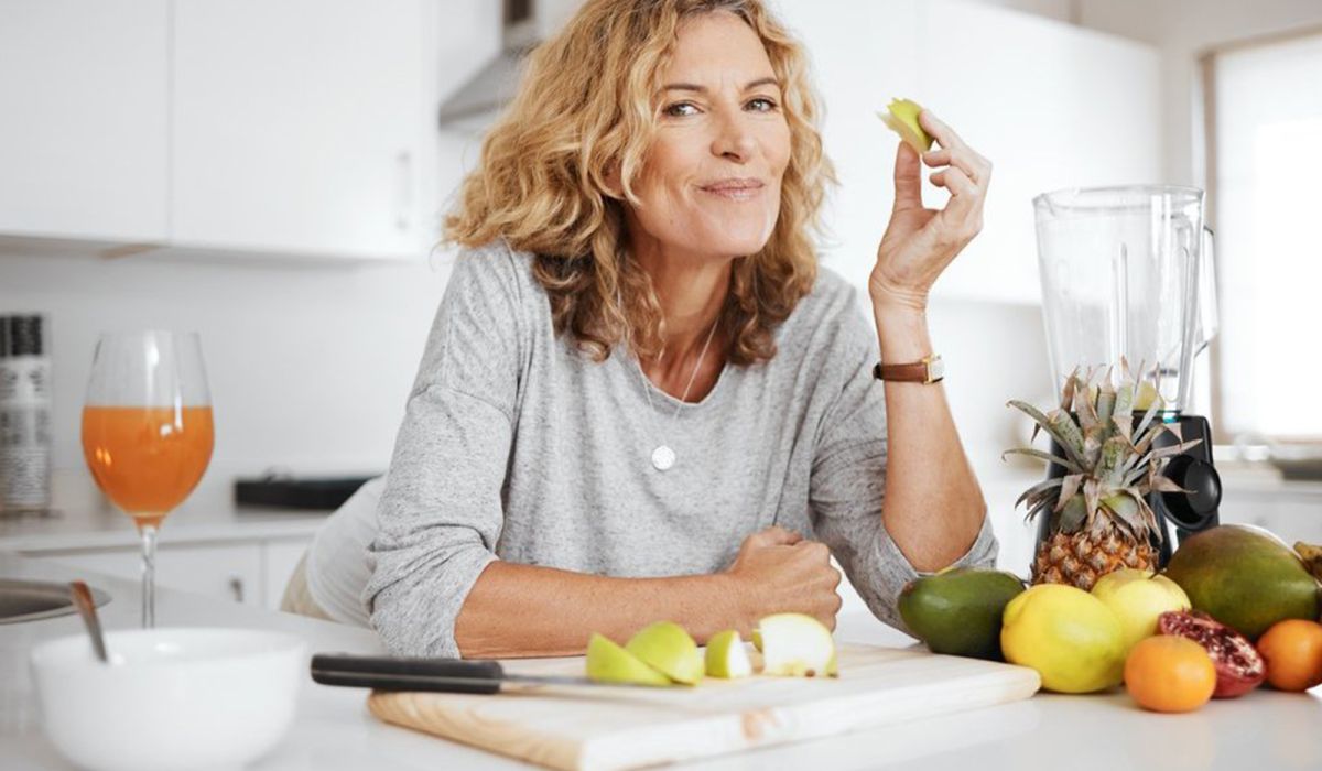 Frau genießt frisches Obst und Gemüse in einer hellen Küche
