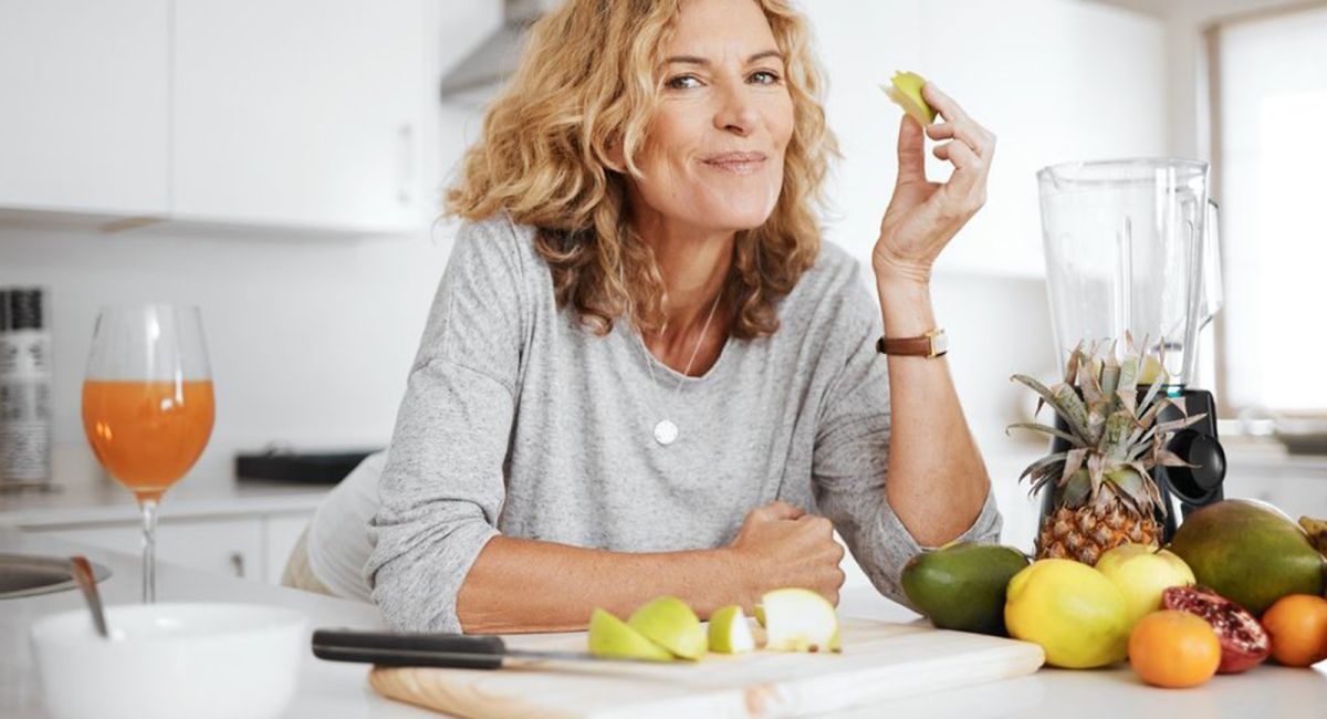 Frau genießt frisches Obst und Gemüse in einer hellen Küche